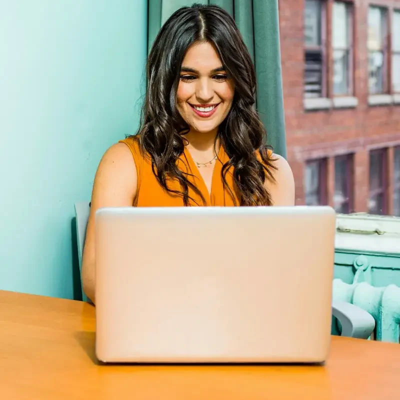 Mulher feliz, trabalhando diante de um computador praticando a produtividade consciente