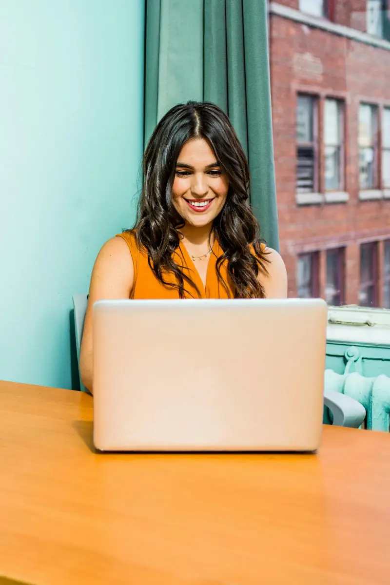 Mulher feliz, trabalhando diante de um computador praticando a produtividade consciente